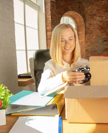 Woman unboxing items from cardboard boxes and looking at a clock